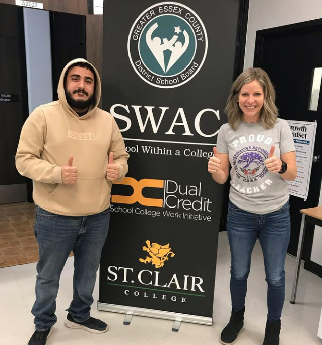 Adult SWAC teacher and student standing in front of a SWAC banner