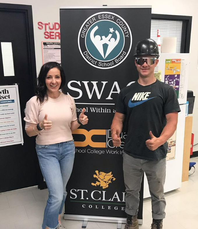 Student and Teacher giving a thumbs up in front of a SWAC banner